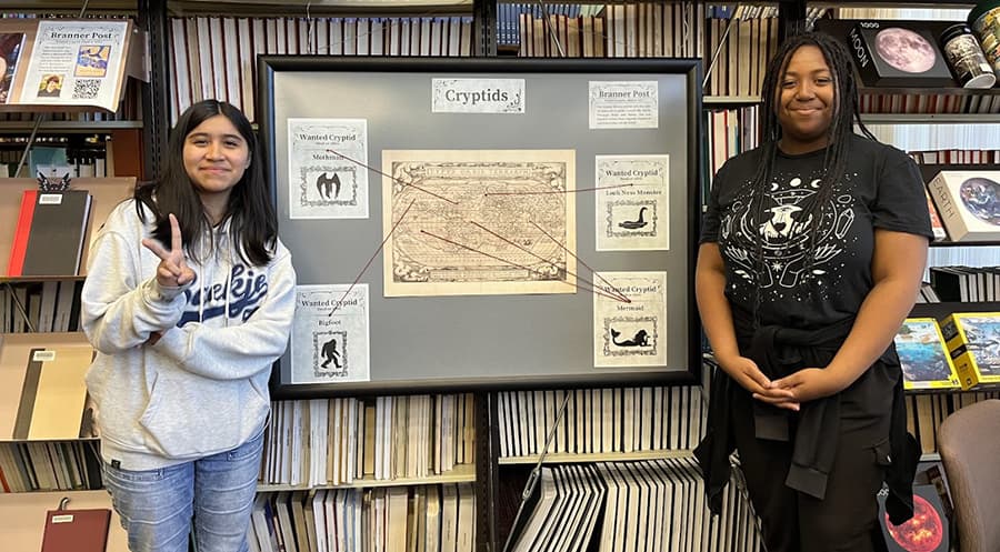 Students standing in front of books and exhibit display.