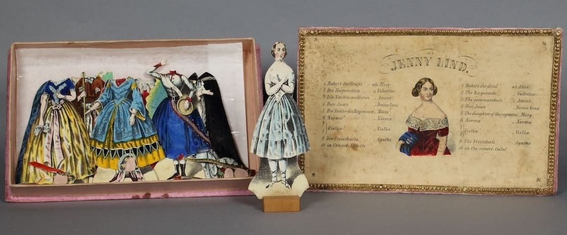Lind paper doll with box and costumes displayed together.