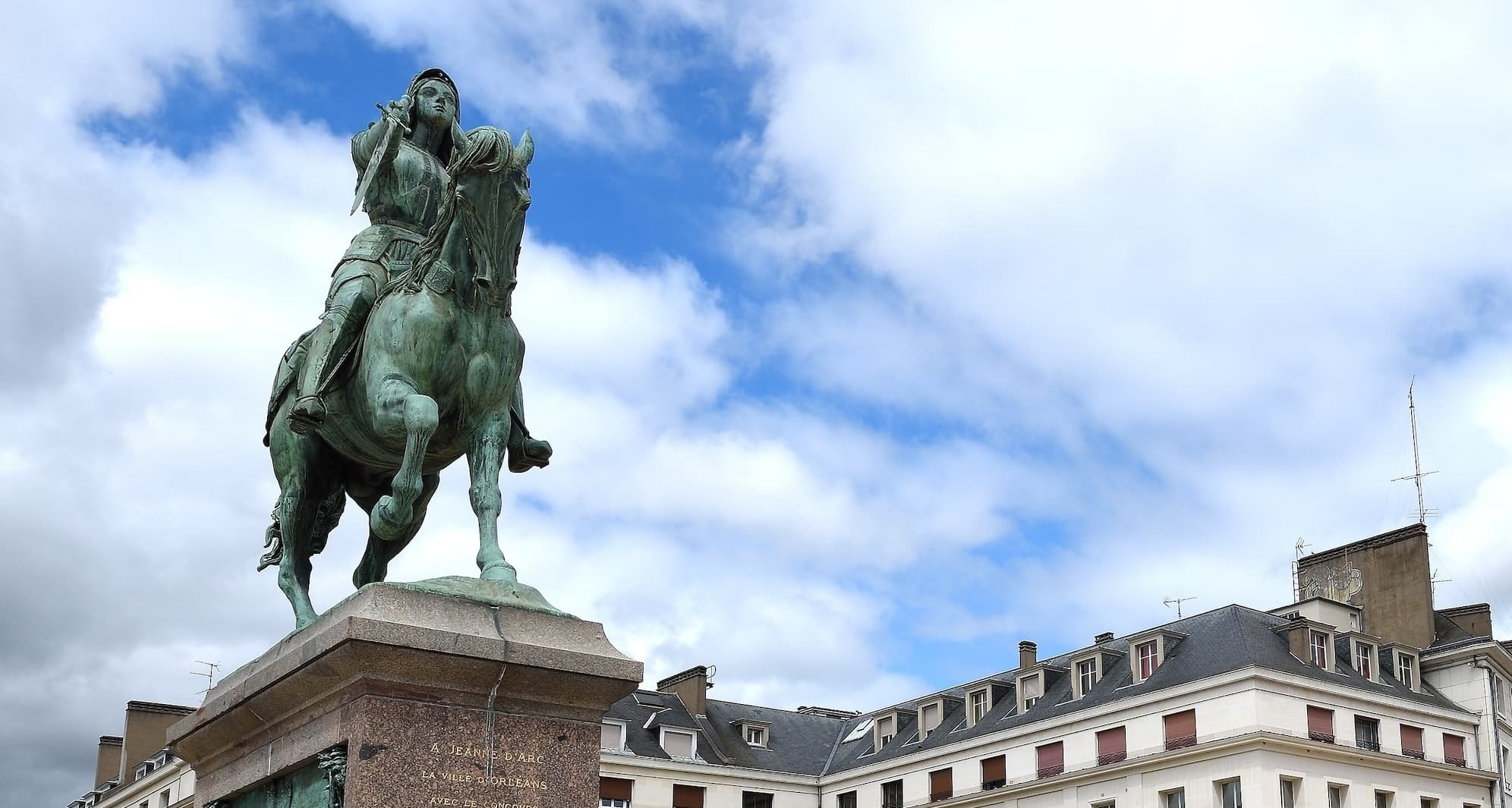 Bronze statue of Joan of Arc, a female warrior with sword in hand, sitting on a horse.